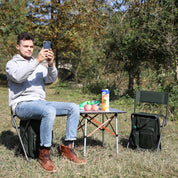 A green folding chair with a built-in cooler bag, designed for outdoor activities like camping or fishing.